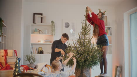 man and women decorating christmas tree with lights