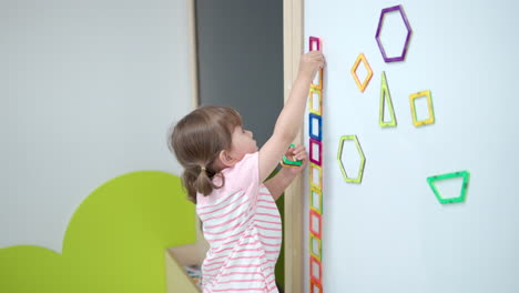 toddler girl playing with magnetic square tiles