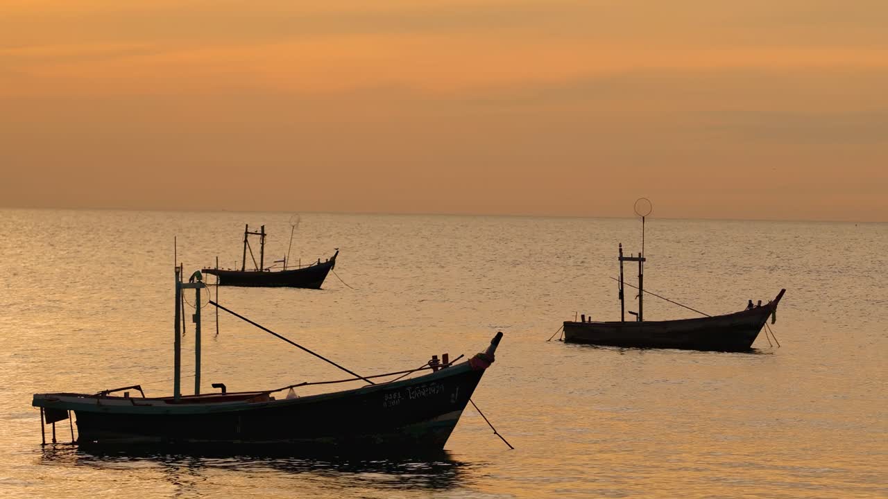 Traditional boats float calmly on the water as the sky glows with warm sunset hues.