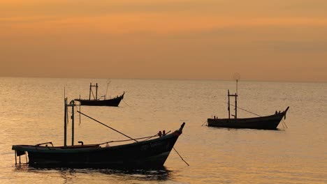 traditional boats float calmly on the water as the sky glows with warm sunset hues.