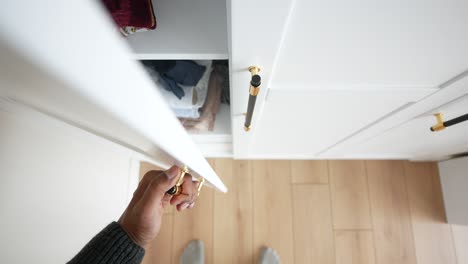 person opening a white cabinet door with gold hardware