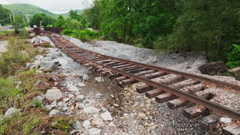 Ein-Aufsteigender-Drohnenschuss-Zeigt-Erodierten-Boden-Unter-Beschädigten-Eisenbahnschienen-Bei-Der-Posthistorischen-Überschwemmung-Im-Jahr-2023-In-Vermont