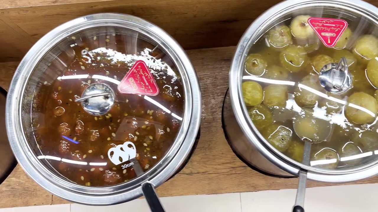 Sottaceti tradizionali, achar misto e confetture di frutta dolci sono esposti in barattoli di vetro all'interno di un negozio di alimentari