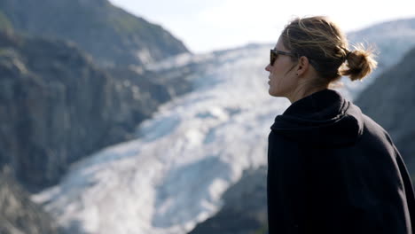 Mujer-Parada-Frente-Al-Glaciar-De-Alaska,-Cámara-Lenta-Cambiando-La-Profundidad-De-La-Toma-De-Enfoque