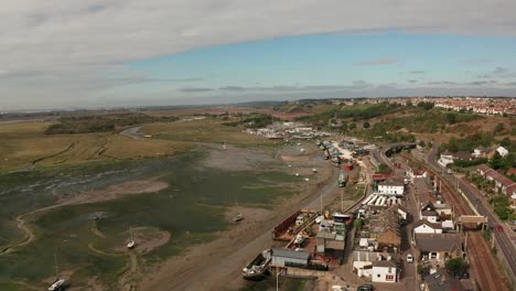 Flying-backwards-over-business-area-wharf-of-coastal-fishing-village-over-marshes