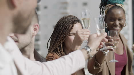 vue latérale de collègues excités portant un toast au champagne en plein air et posant pour la photo