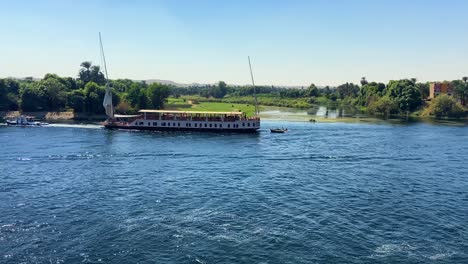 cinematic video of a large egyptian cruise boat sailing along the banks of the green nile river valley during a vacation