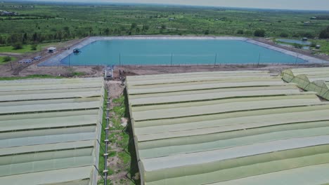 flying above greenhouses on farmland towards irrigation basin