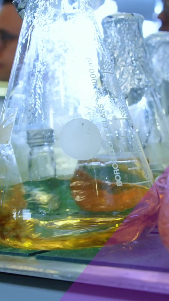 Animation of purple ribbon against chemicals in flasks spinning on magnetic stirrer at laboratory
