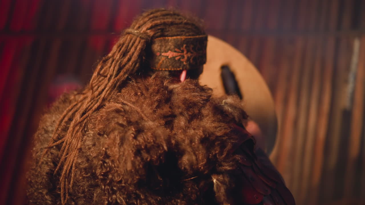 긴 드레드머리와 모피 옷을 입은 남자가  ⁇ 버린을 연주합니다.