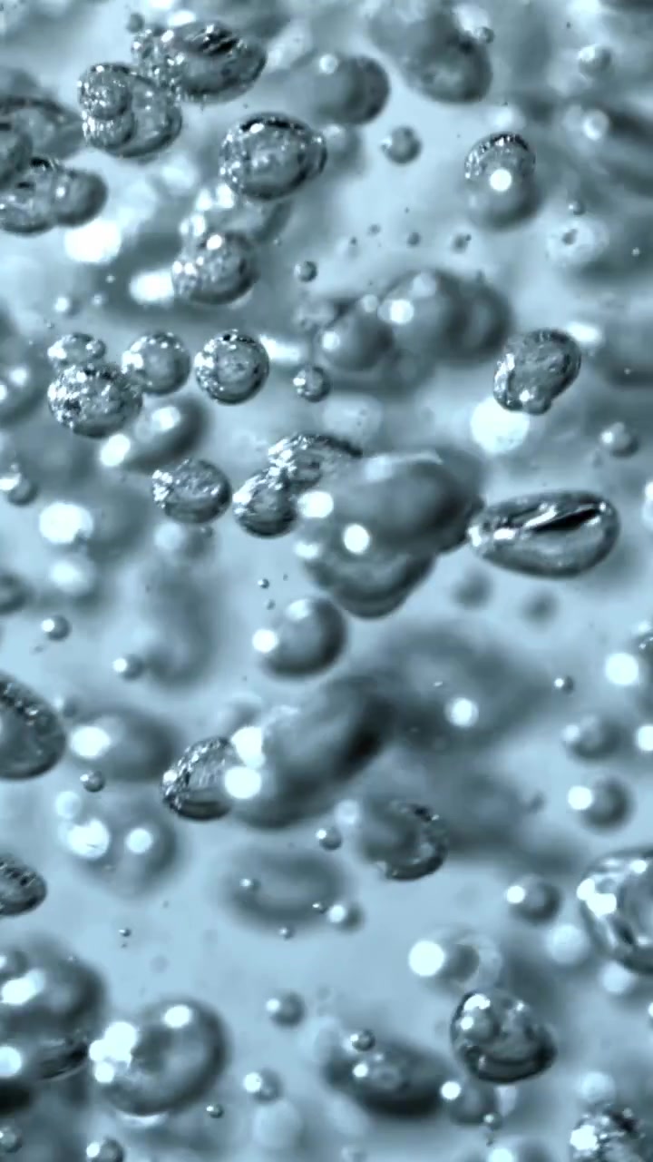 Primo piano macro di bolle d'aria lucide che salgono in acqua limpida