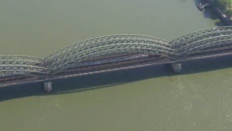 Un-Tren-Cruzando-El-Puente-Hohenzollern-Sobre-El-Rin,-Colonia,-Vista-Aérea