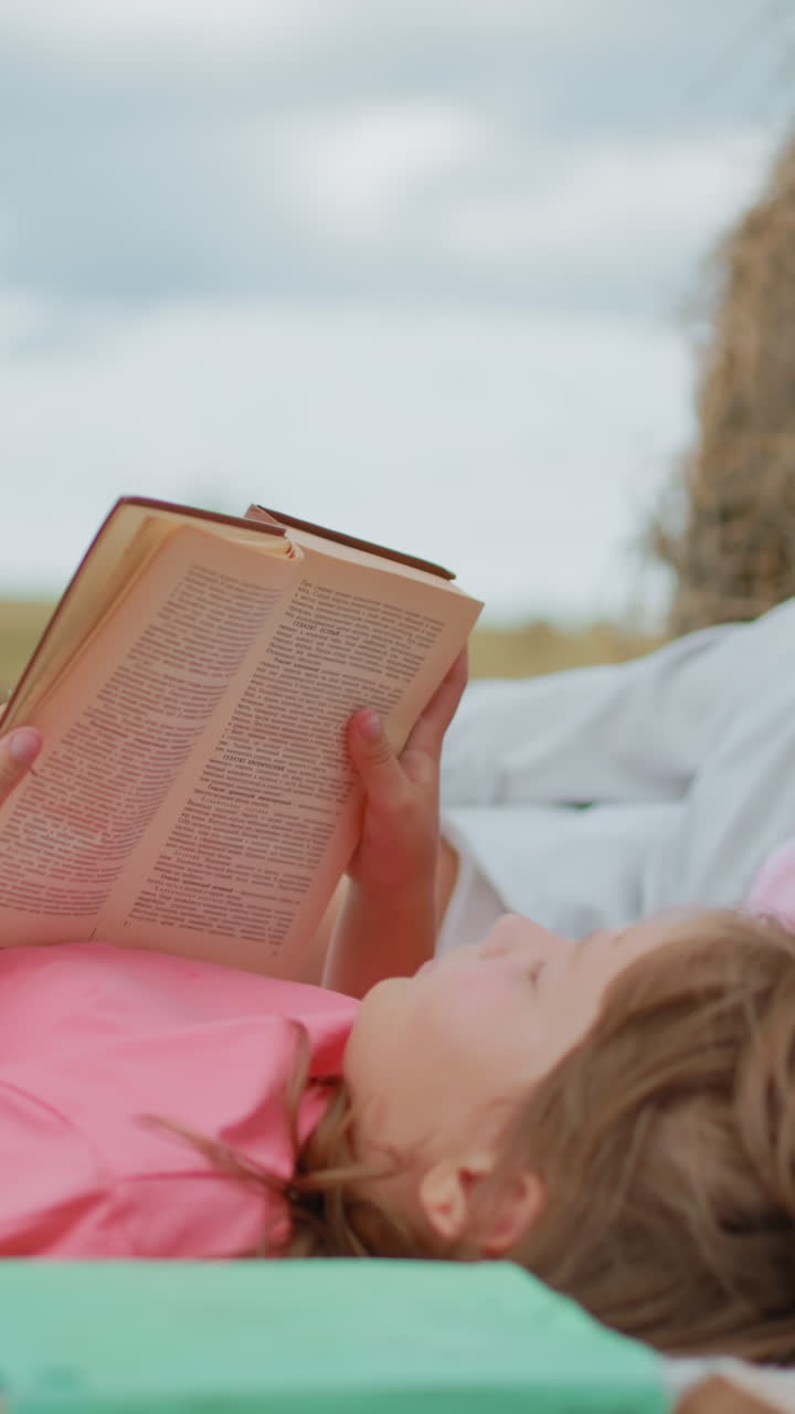 familia disfrutando de un tranquilo picnic en una manta en una vasta tierra de cultivo, madre e hija relajadas con libros, perro descansando a su lado, hermoso momento de unión familiar al aire libre en la naturaleza