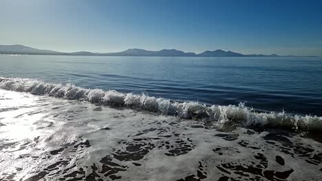 Slow-motion-sea-tide-splashing-under-heavenly-hazy-sunrise-Snowdonia-mountain-range-skyline