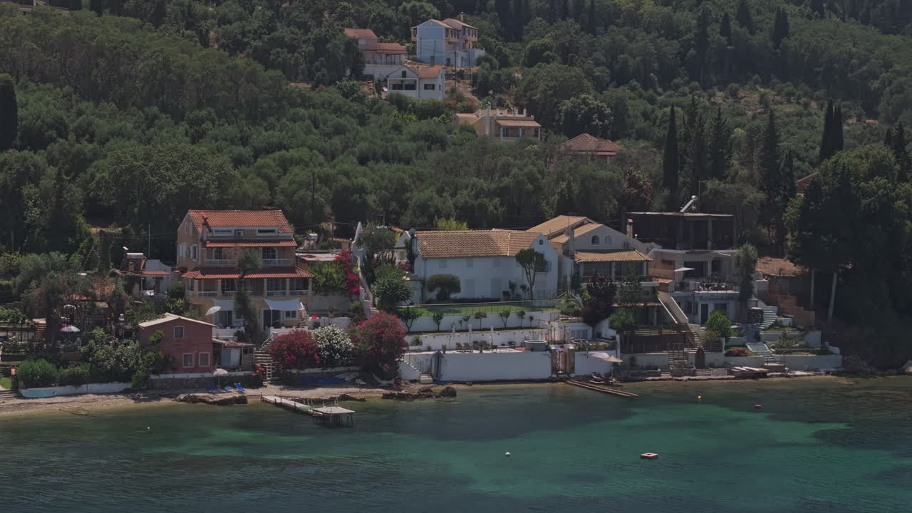 Corfu Island Greece Aerial v4 zoomed low flyover the sea capturing serene seaside villas in Psaras village, framed by lush hills and crystal clear waters - Shot with Mavic 3 Pro Cine - July 16th 2024