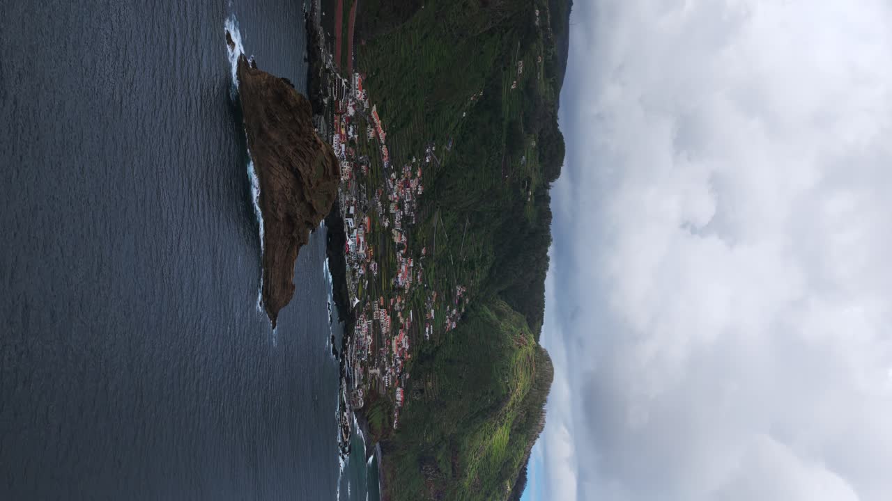 Aerial view of Porto Moniz, houses, volcanic islet and coastline in Madeira Island, Portugal. Vertical Video