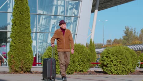 senior pensioner tourist grandfather businessman walking from airport hall gate with luggage bag