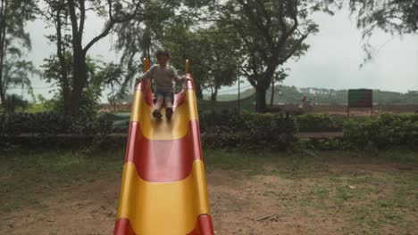 little children playing on a slide in a yellow and red colored park