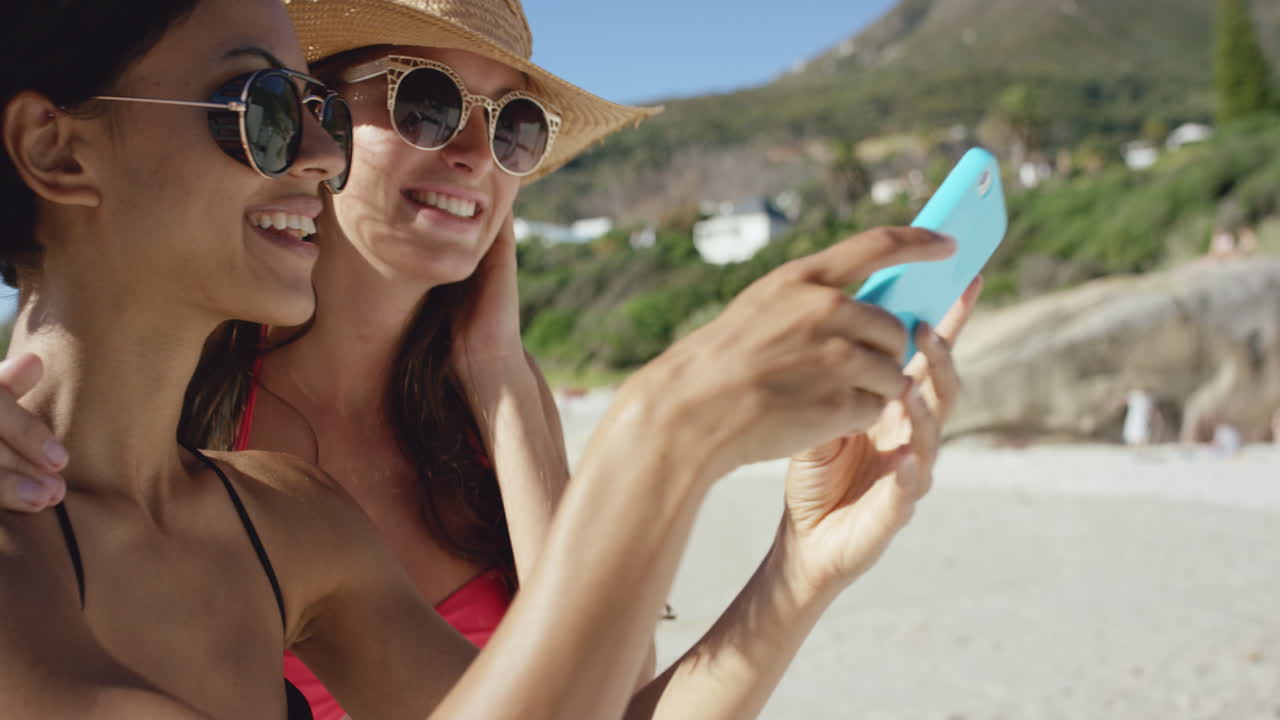 dos amigos tomando selfies en la playa