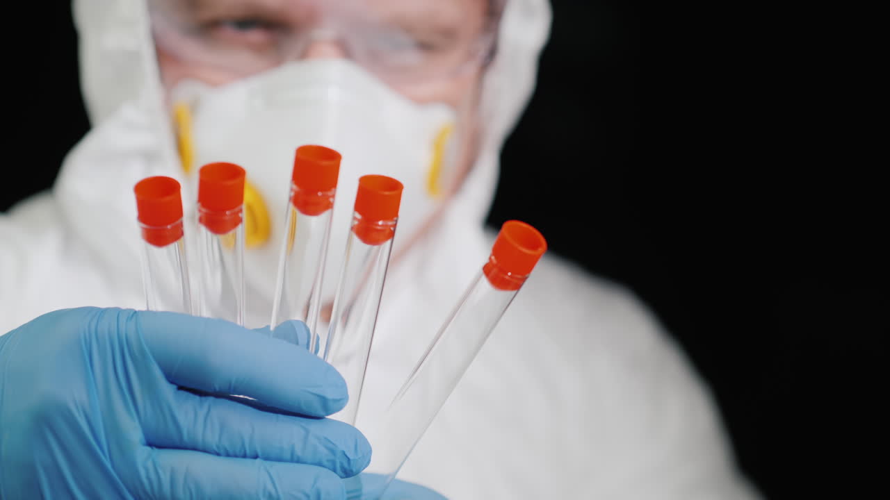 un investigador con traje protector sostiene varios tubos de ensayo