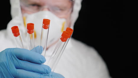 A-researcher-in-a-protective-suit-holds-several-test-tubes