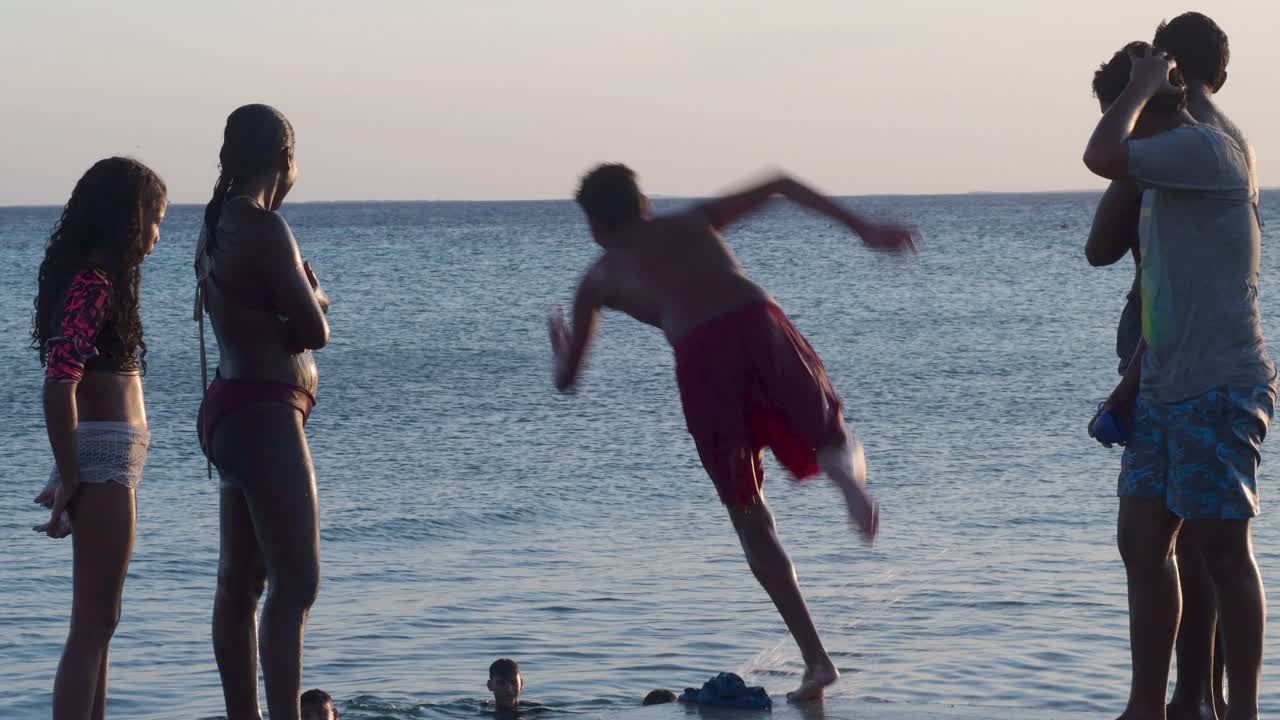 Group Young Hispanic Heritage having fun on sunset beach, jumping into sea water, Venezuela