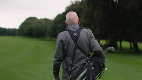 man carrying golf bag on course