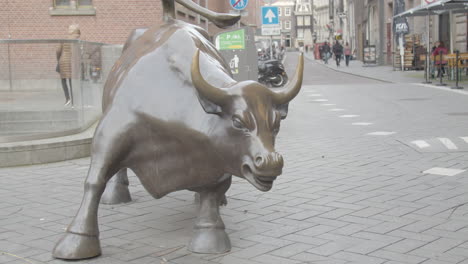 primer plano del toro frente a la bolsa de valores de amsterdam con gente caminando en el fondo