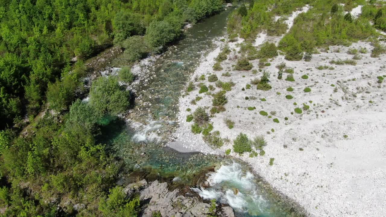 Drone-näkymä Albaniassa Alpeilla, lennokki lentää vihreän ja sinisen veden joen yli vihreässä laaksossa Thethissä.