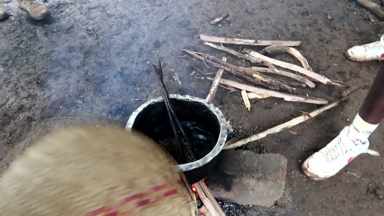 gente de la tribu chagga local africana vertiendo granos de café tamizados en un cubo de metal para asarlos en la chimenea