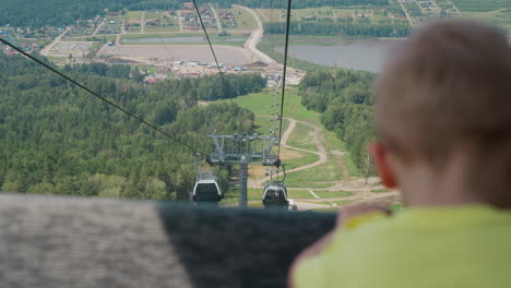 Little-boy-looks-at-valley-with-road-and-lake-from-ropeway