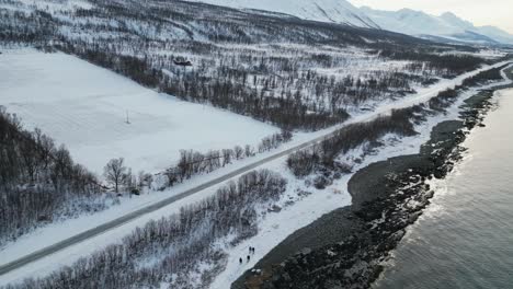 drone shot of highway in tromso norway during winter with snow near water