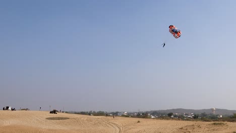 Parasailing-Abenteueraktivität-In-Der-Wüste-Mit-Strahlend-Blauem-Himmelshintergrund-Am-Tag-Aus-Flachem-Winkel