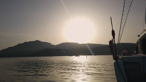 Breite-Aufnahme-Eines-Mannes-Steht-Auf-Surfbrett-In-Der-Ferne-Und-Boote-Im-Hintergrund-Während-Des-Sonnenuntergangs