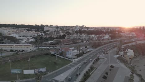 Vista-Aérea-Del-Horizonte-De-La-Ciudad-De-La-Noche-Al-Amanecer-Del-Día-En-Lisboa-Con-Algunos-Autos-Moviéndose-Sobre-Marginal