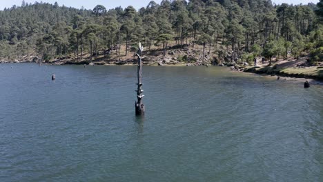 órbita aérea que rodea el tronco de un árbol vertical flotando en posición vertical en el lago del bosque azul