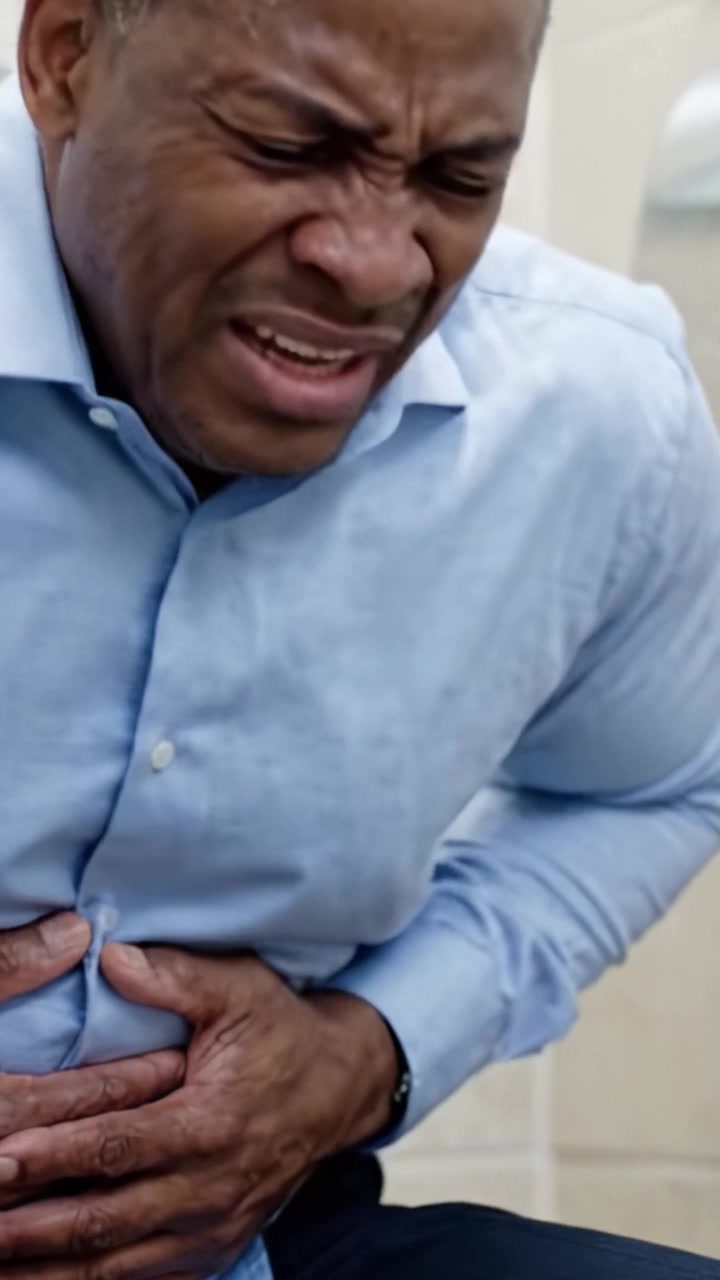 A Man Experiencing Severe Abdominal Pain in a Restroom, Showing Signs of Distress and Discomfort due to an Acute Medical Condition