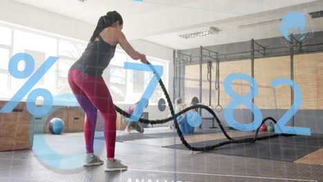 animation of interface processing data over caucasian woman cross training with battle ropes at gym