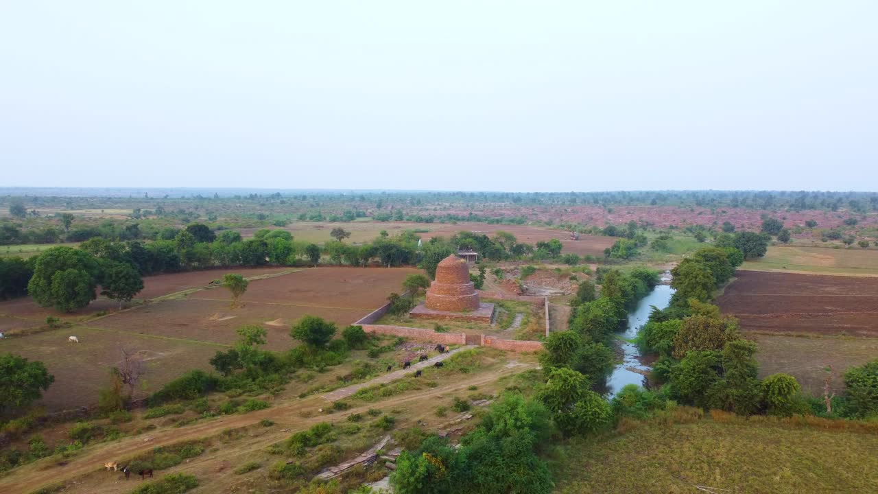 Ripresa aerea con drone di un antico Stupa Buddista realizzato con una struttura in mattoni di roccia in un villaggio attraversato da un fiume a Shivpuri, Madhya Pradesh, in India.