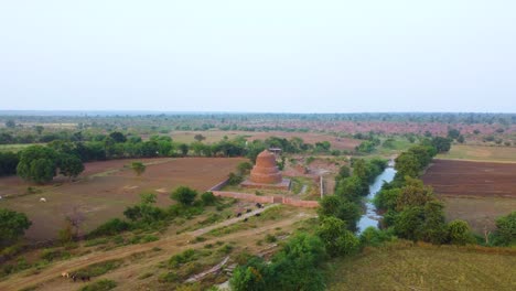 Aerial-drone-shot-of-Ancient-Buddhist-Stupa-made-from-rock-brick-structure-in-a-village-with-river-flowing-in-Shivpuri-Madhya-Pradesh-in-India