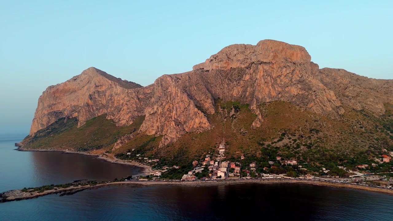 Prospettiva aerea all'ora d'oro dell'imponente promontorio roccioso di Capo Gallo illuminato dalla calda luce del tramonto vicino a Sferracavallo, Sicilia.