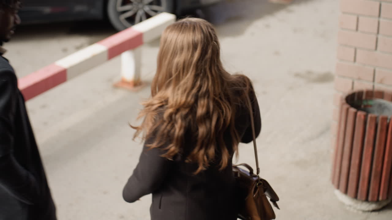 Unos encuadres de cámara capturan la entrada de un edificio con un pilar de ladrillo y una barandilla de metal, mientras que una papelera de madera se sitúa en un fondo con un desenfoque suave. Una luz tenue y unas líneas limpias crean un momento urbano de calma con texturas.