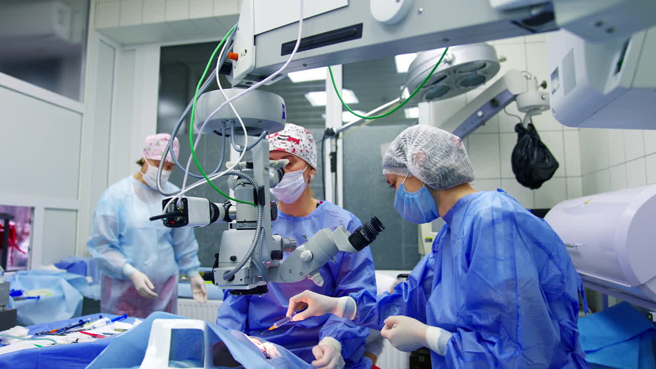 Medical team performing eye surgery. Surgeon looking into the microscope at the eye of patient at the operating room