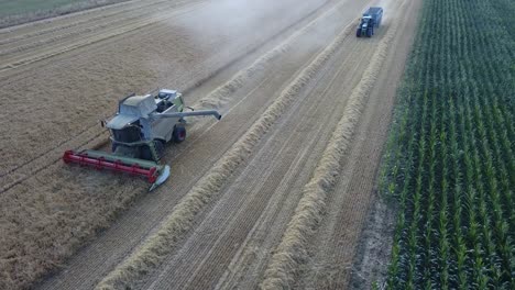 Eine-Filmische-4K-Drohnenaufnahme-Eines-Mähdreschers-Und-Eines-Traktors-Bei-Der-Ernte-Eines-Feldes-In-Frankreich,-Die-Die-Landwirtschaft-Mit-Einer-Epischen-Aussicht-Und-Dramatischem-Staub-Zeigt