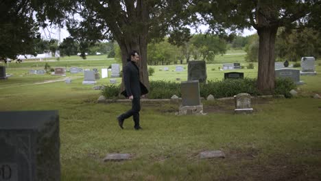 man in black suit walking in cemetery in slow motion