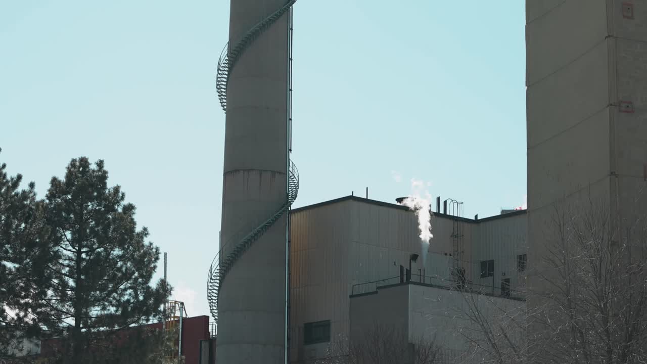 View of a old factory in downtown Hull, Quebec from the outside on a sunny day showing off the smoke stack and back yard of the building