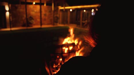 camera behind a person at its right side looking at bonfire