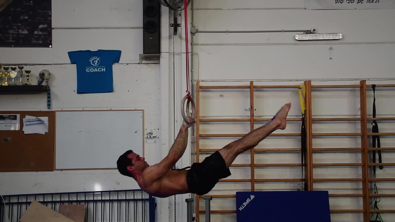 una foto fija de un tipo haciendo ejercicio en los anillos fijos de un aparato de gimnasia que es extremadamente duro en cámara lenta de 60 fps