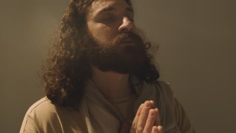 Studio-Portrait-Of-Man-Wearing-Robes-With-Long-Hair-And-Beard-Representing-Figure-Of-Jesus-Christ-Praying-2