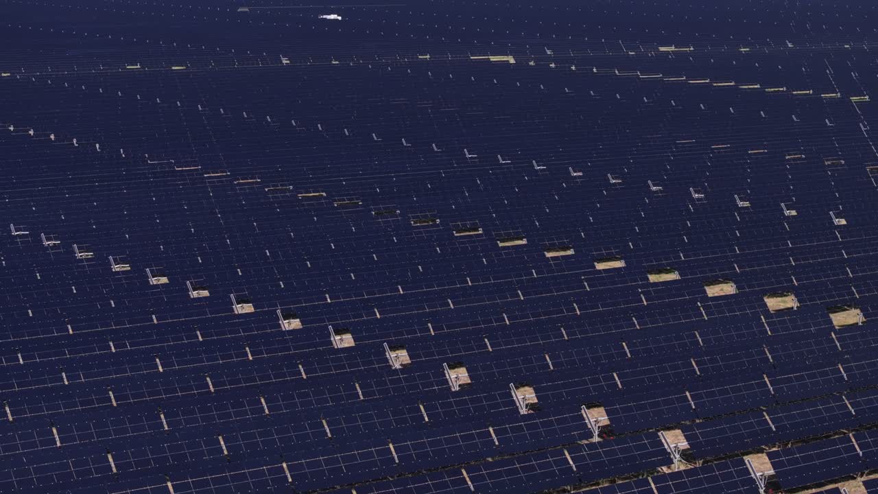 Rows of solar panels absorbing sunlight, seen from an aerial view on a clear day
